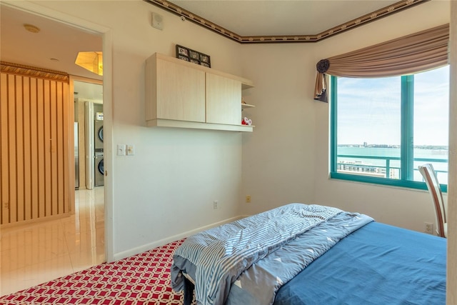 bedroom with a water view, crown molding, and stacked washer and clothes dryer