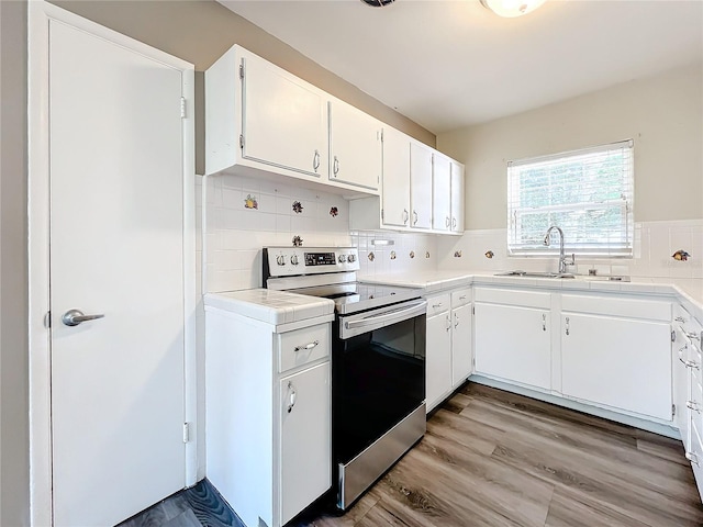 kitchen with backsplash, sink, electric range, light hardwood / wood-style flooring, and white cabinets