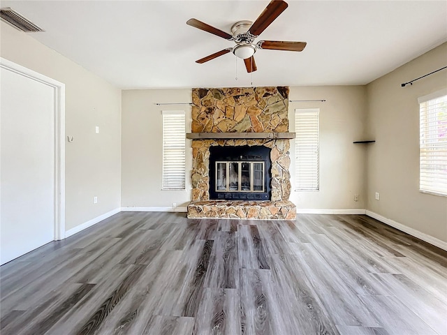 unfurnished living room featuring a stone fireplace, ceiling fan, and hardwood / wood-style floors