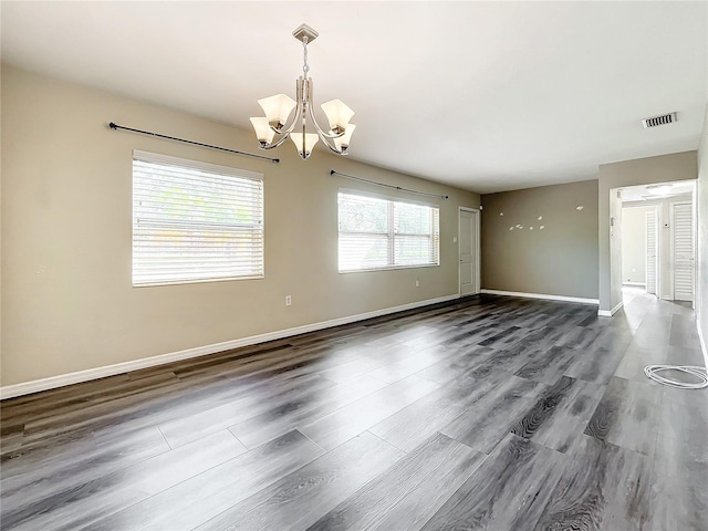 empty room with dark hardwood / wood-style flooring and a notable chandelier