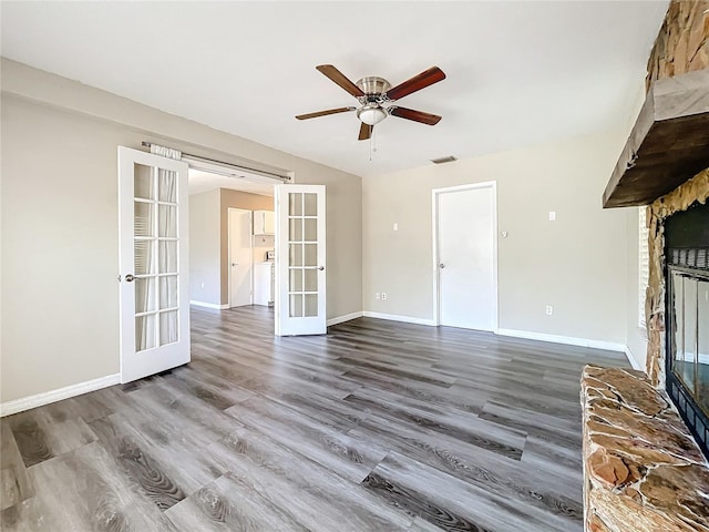 unfurnished living room with a fireplace, french doors, hardwood / wood-style flooring, and ceiling fan