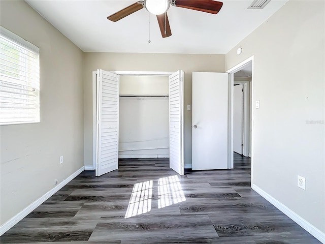 unfurnished bedroom with ceiling fan, dark wood-type flooring, and a closet