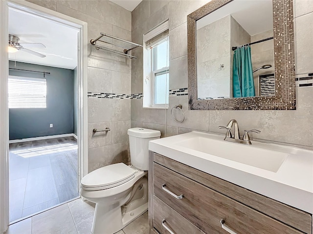 bathroom with vanity, tile patterned floors, ceiling fan, toilet, and tile walls