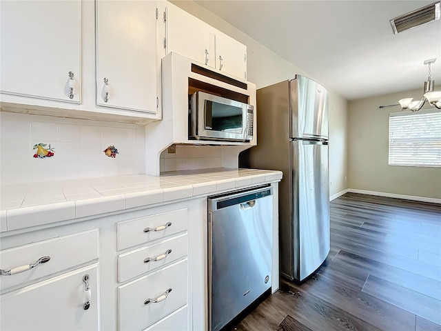 kitchen with stainless steel appliances, tile counters, tasteful backsplash, visible vents, and white cabinetry