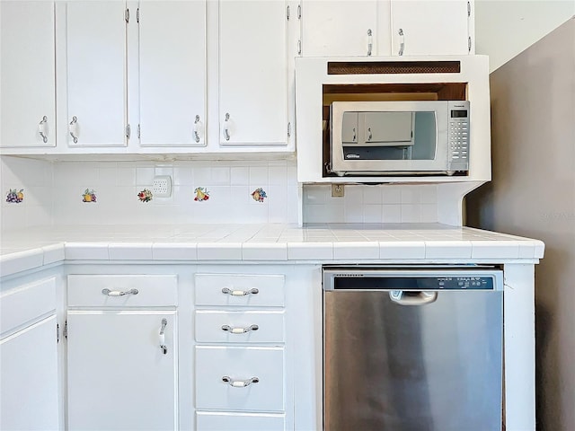 kitchen featuring tile countertops, appliances with stainless steel finishes, white cabinets, and decorative backsplash