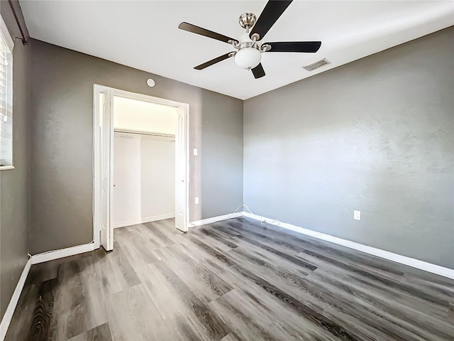 unfurnished bedroom with a ceiling fan, wood finished floors, visible vents, and baseboards