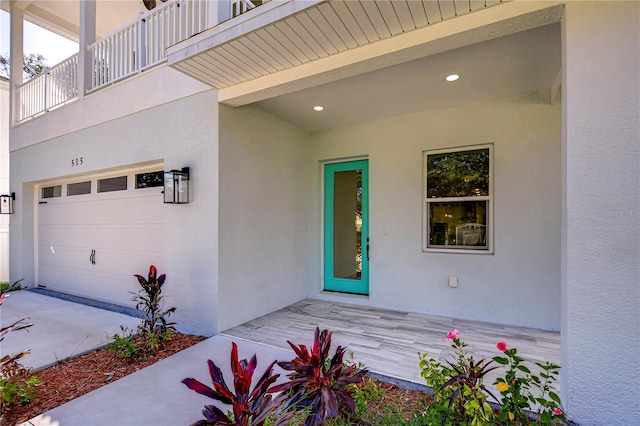 view of exterior entry featuring a garage and a balcony