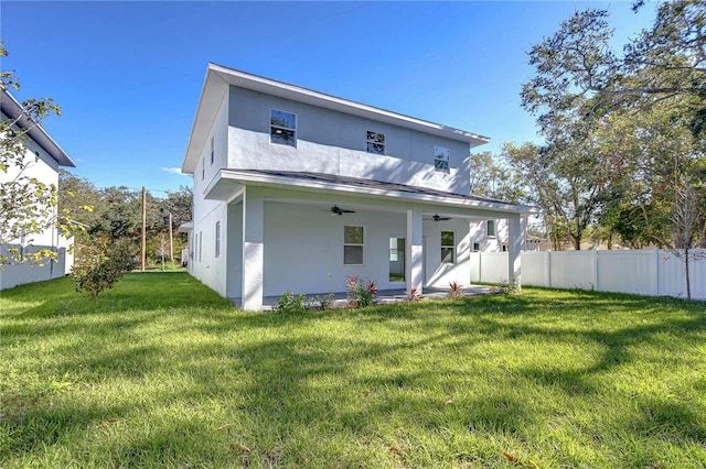 rear view of property featuring a lawn, ceiling fan, and a patio