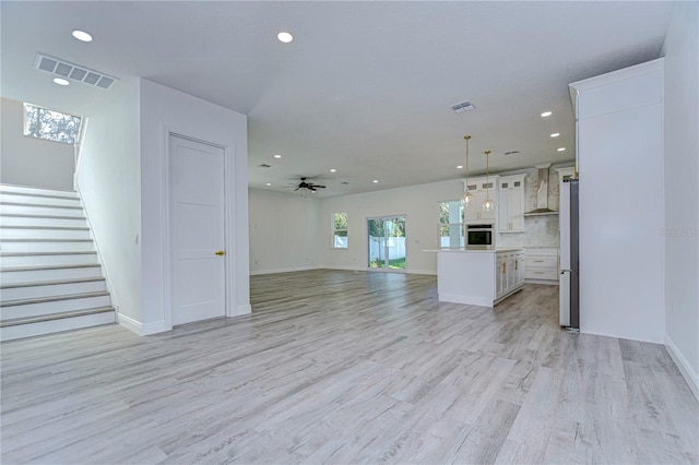 unfurnished living room featuring ceiling fan and light wood-type flooring