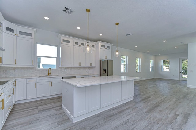 kitchen with white cabinets, stainless steel fridge with ice dispenser, plenty of natural light, and a kitchen island