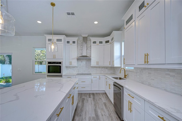 kitchen with hanging light fixtures, wall chimney exhaust hood, stainless steel appliances, and sink