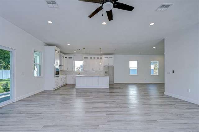 unfurnished living room featuring light hardwood / wood-style floors, ceiling fan, and a healthy amount of sunlight