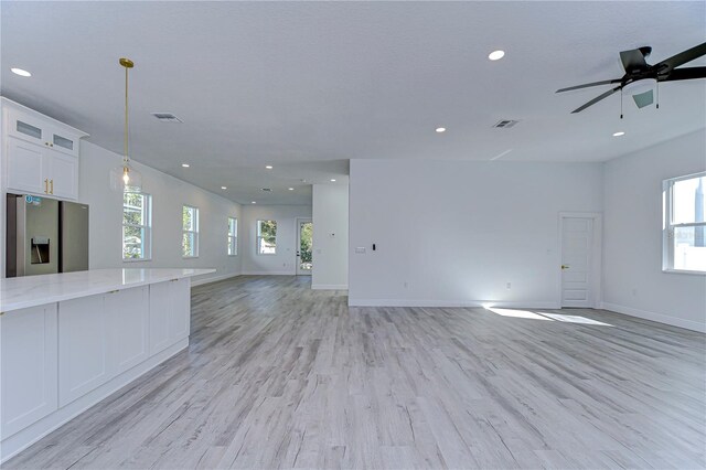 unfurnished living room with ceiling fan, plenty of natural light, and light hardwood / wood-style flooring