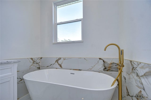 bathroom featuring a bathing tub, a healthy amount of sunlight, and tile walls