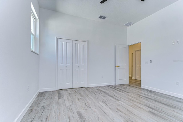 unfurnished bedroom featuring ceiling fan, light hardwood / wood-style floors, a textured ceiling, and a closet