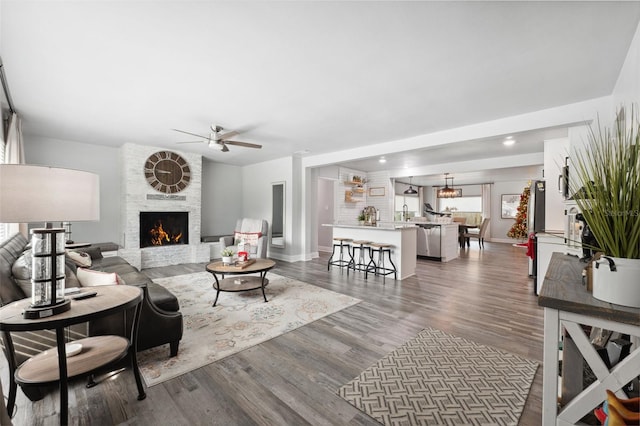 living room featuring dark wood-type flooring, ceiling fan, and a fireplace