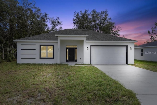 view of front of property with a garage and a yard