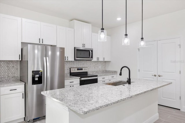 kitchen featuring light stone countertops, sink, a kitchen island with sink, white cabinets, and appliances with stainless steel finishes