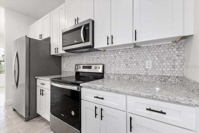 kitchen featuring white cabinets, decorative backsplash, light wood-type flooring, and stainless steel appliances