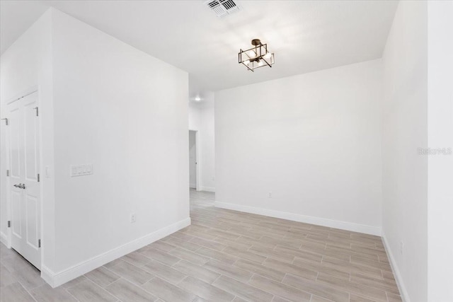 empty room with an inviting chandelier and light hardwood / wood-style flooring