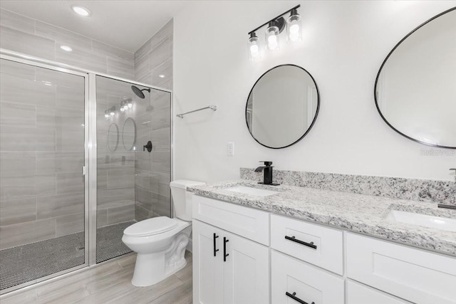 bathroom featuring vanity, hardwood / wood-style flooring, toilet, and a shower with door