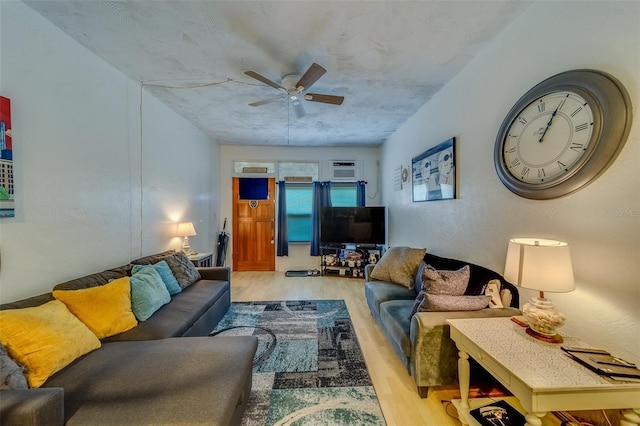 living room with a wall unit AC, ceiling fan, and light hardwood / wood-style floors