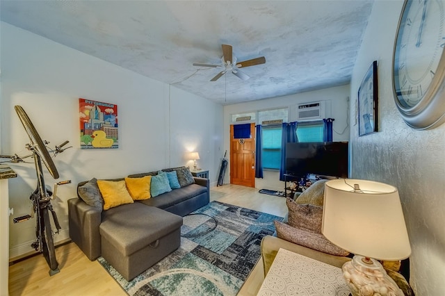 living room with light hardwood / wood-style floors, a wall unit AC, and ceiling fan