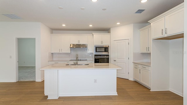 kitchen featuring a kitchen island with sink, backsplash, black appliances, and white cabinets