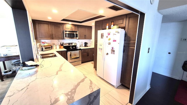 kitchen featuring sink, light stone countertops, appliances with stainless steel finishes, tasteful backsplash, and light tile patterned flooring