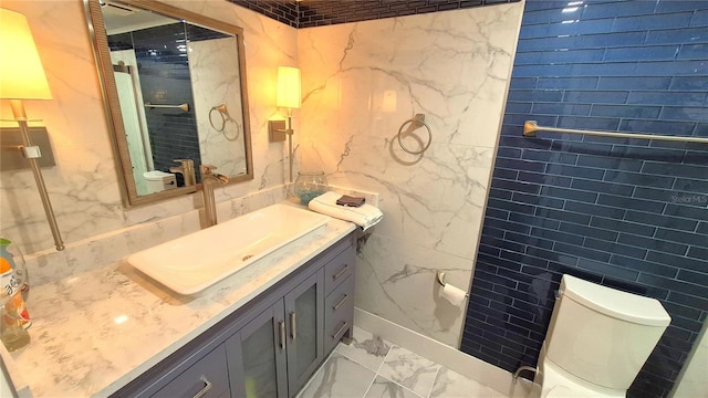 bathroom featuring vanity, tile walls, and toilet