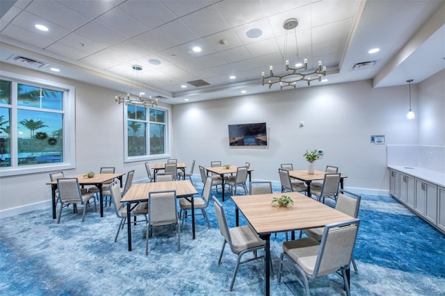 dining room featuring a tray ceiling, dark carpet, and an inviting chandelier