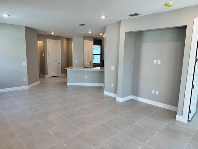 unfurnished living room featuring light tile patterned floors and sink