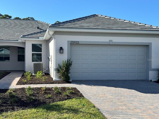 view of front of home with a garage and central air condition unit