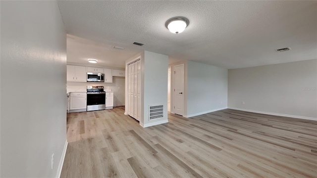 interior space with a textured ceiling and light hardwood / wood-style flooring