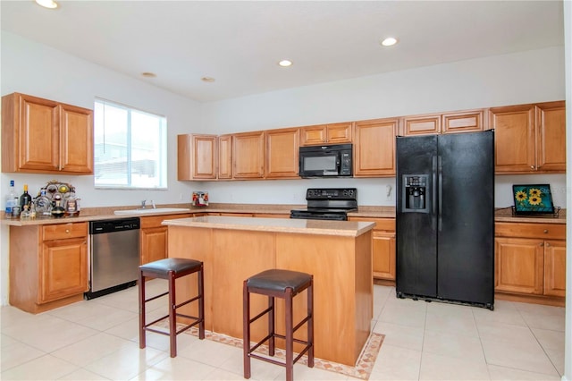 kitchen featuring sink, a kitchen island, a kitchen bar, light tile patterned flooring, and black appliances