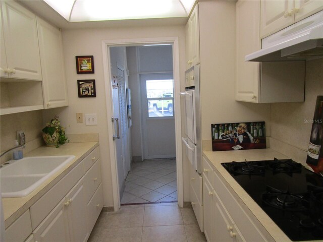6000 20th St N Unit 114, Saint Petersburg, FL 33714 - kitchen with black cooktop, a sink, under cabinet range hood, and white cabinets
