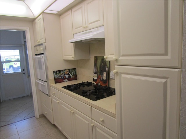 6000 20th St N Unit 114, Saint Petersburg, FL 33714 - kitchen featuring under cabinet range hood, a warming drawer, black gas cooktop, oven, and light countertops