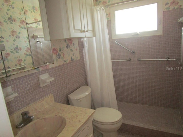 6000 20th St N Unit 114, Saint Petersburg, FL 33714 - bathroom featuring tiled shower, toilet, a wainscoted wall, vanity, and tile walls