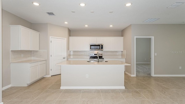 kitchen with white cabinetry, appliances with stainless steel finishes, sink, and an island with sink