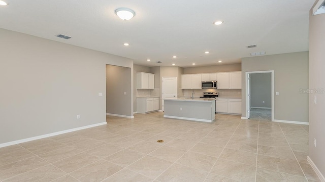 kitchen with sink, white cabinetry, tasteful backsplash, a center island with sink, and stainless steel appliances