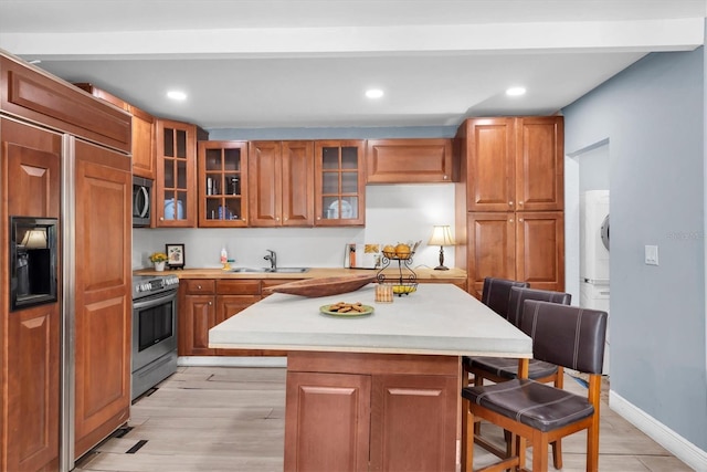 kitchen with a kitchen breakfast bar, light hardwood / wood-style flooring, stainless steel appliances, and sink