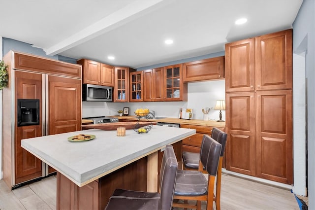 kitchen with a breakfast bar, a kitchen island, stainless steel appliances, and light hardwood / wood-style flooring