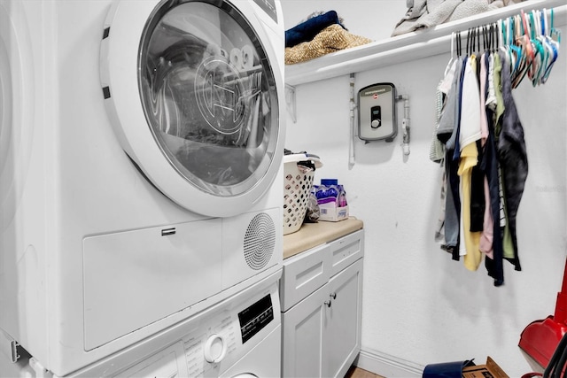 clothes washing area with cabinets and stacked washer / drying machine