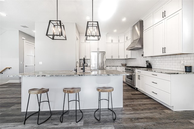 kitchen featuring dark hardwood / wood-style flooring, a center island with sink, wall chimney range hood, and high end appliances