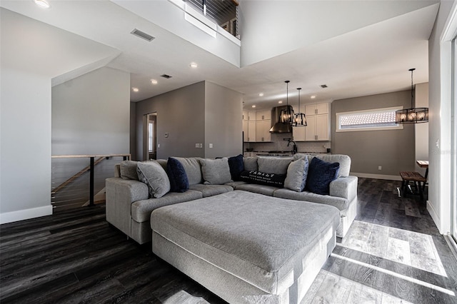 living room featuring a high ceiling, dark hardwood / wood-style floors, and a notable chandelier