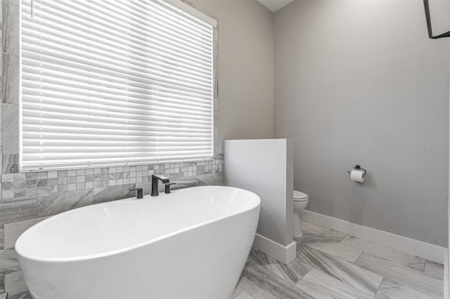 bathroom featuring a bath, tile walls, and toilet