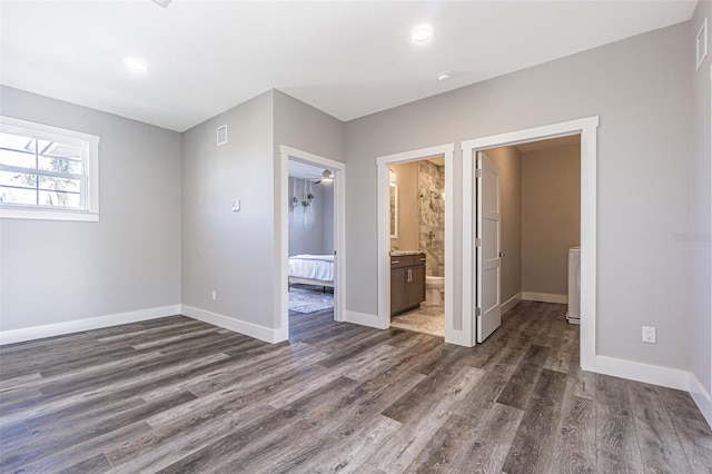 unfurnished bedroom with connected bathroom and dark hardwood / wood-style floors