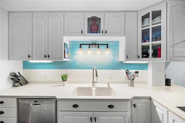 kitchen with stainless steel dishwasher, white cabinets, sink, and tasteful backsplash