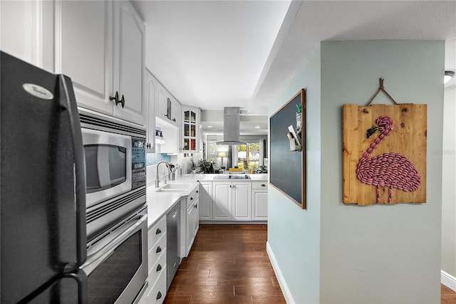 kitchen with sink, dark hardwood / wood-style flooring, white cabinetry, island exhaust hood, and stainless steel appliances