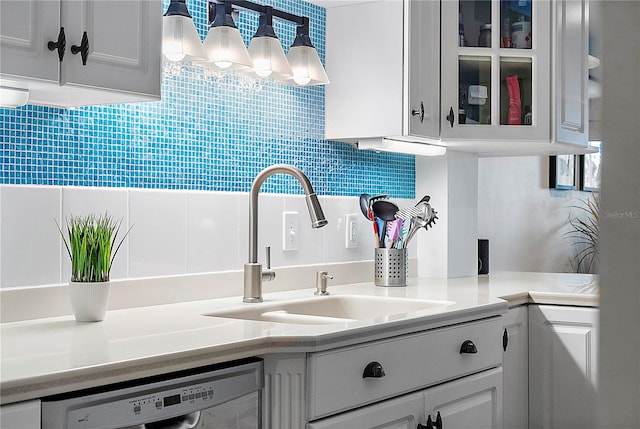 kitchen featuring white cabinets, white dishwasher, tasteful backsplash, and sink